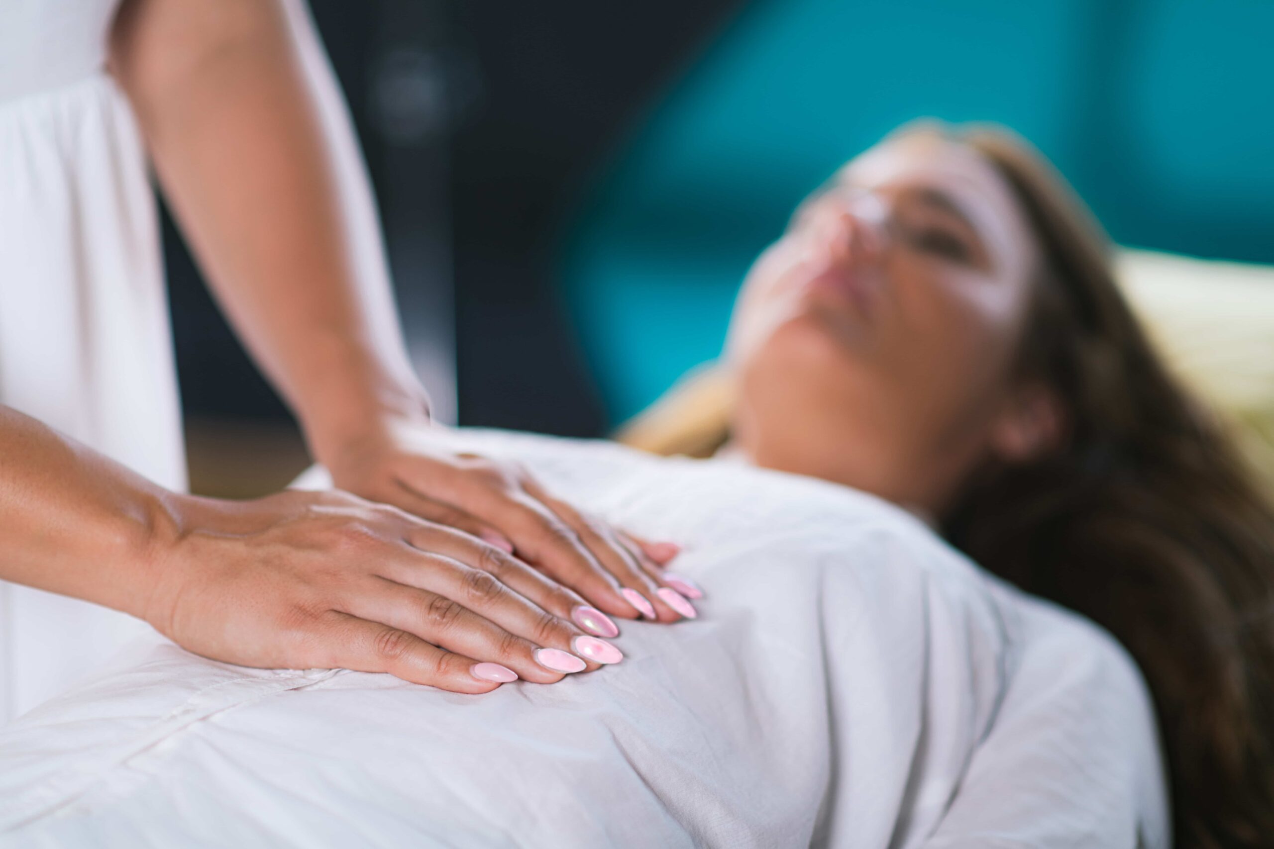 Holistic approach to health, a woman's hands practising Reiki healing treatment on another woman.