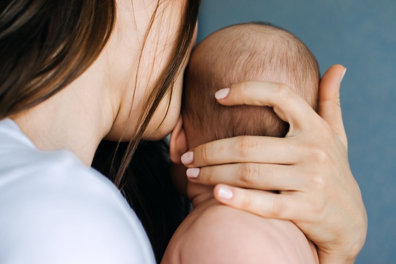 postnatal massage; a mother kissing her baby