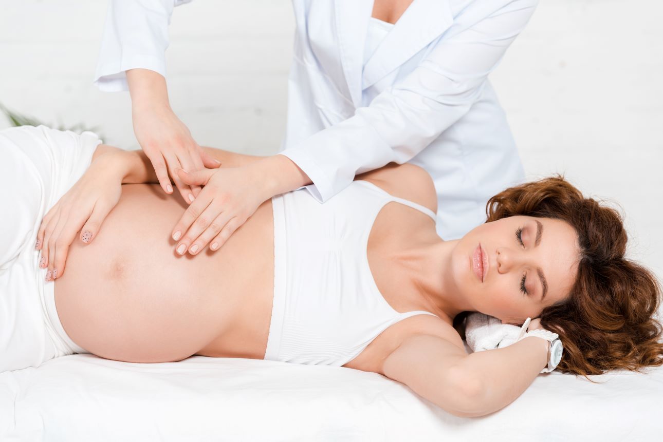 a pregnant woman receiving pregnancy reflexology treatment from a therapist