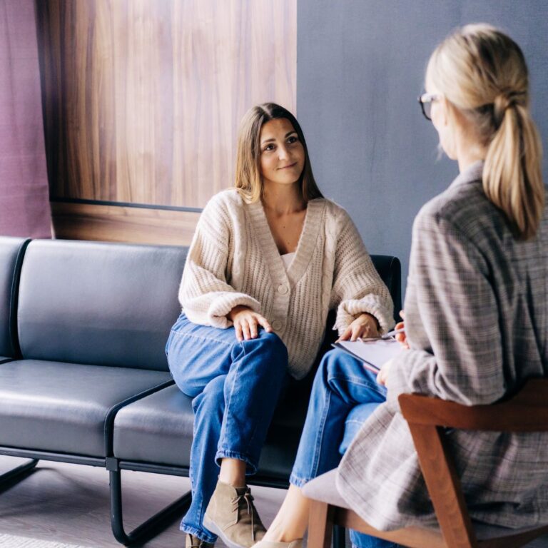 A serene wellness studio with a therapist attentively listening to a client in a supportive and calming environment. Elements like a massage table, aromatherapy oils, and plants add to the therapeutic atmosphere.