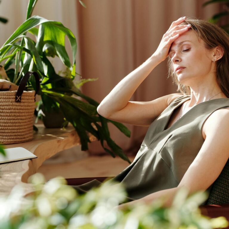 A thoughtful woman resting with eyes closed in a calm, softly lit space, symbolizing emotional stillness and gentle self-reflection during a healing journey